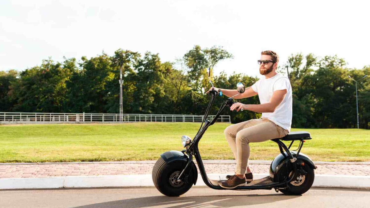 cool bearded man in sunglasses rides on modern motorbike outdoors