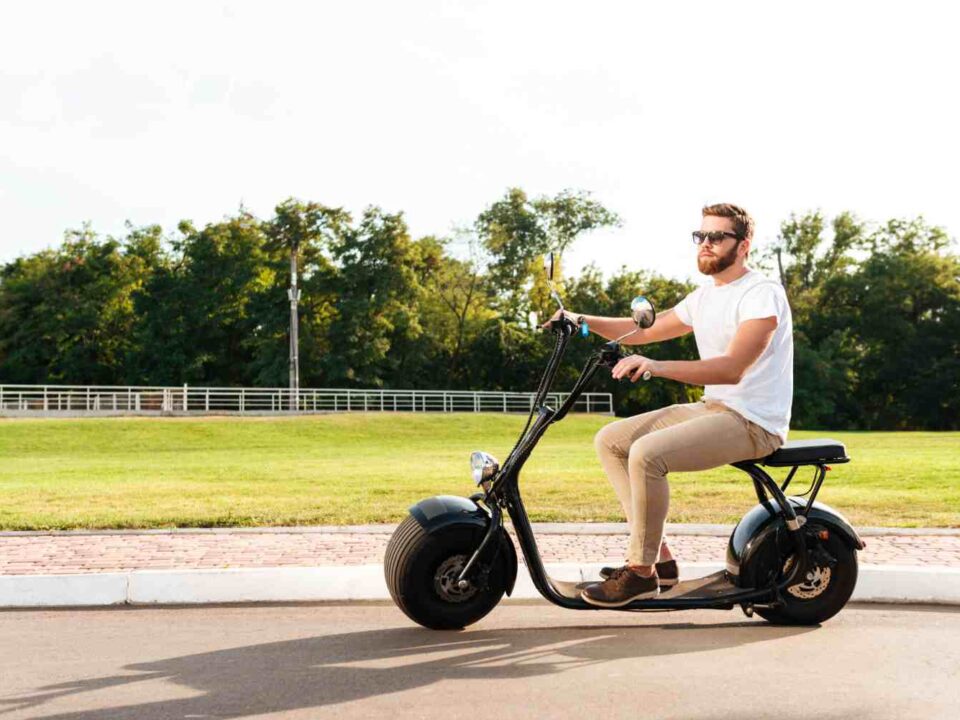 cool bearded man in sunglasses rides on modern motorbike outdoors